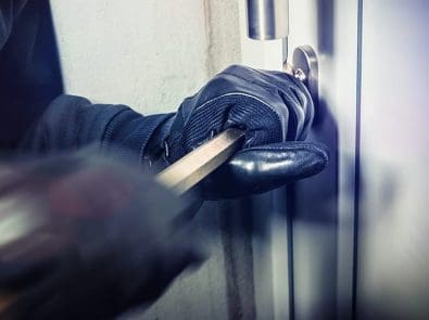 a burglar prying open a door with a crowbar