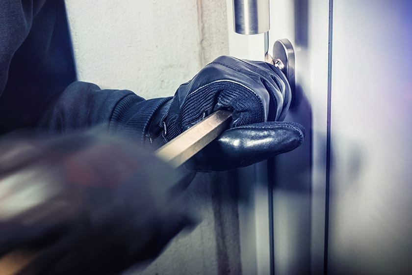 a burglar prying open a door with a crowbar