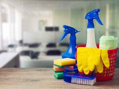 a basket with spray bottles, sponges and rubber gloves