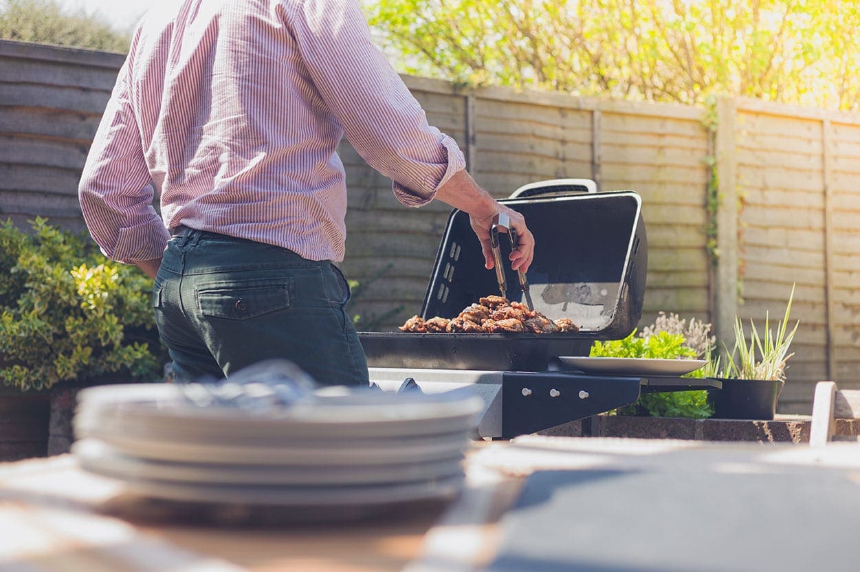 a man grilling meat in a backyard