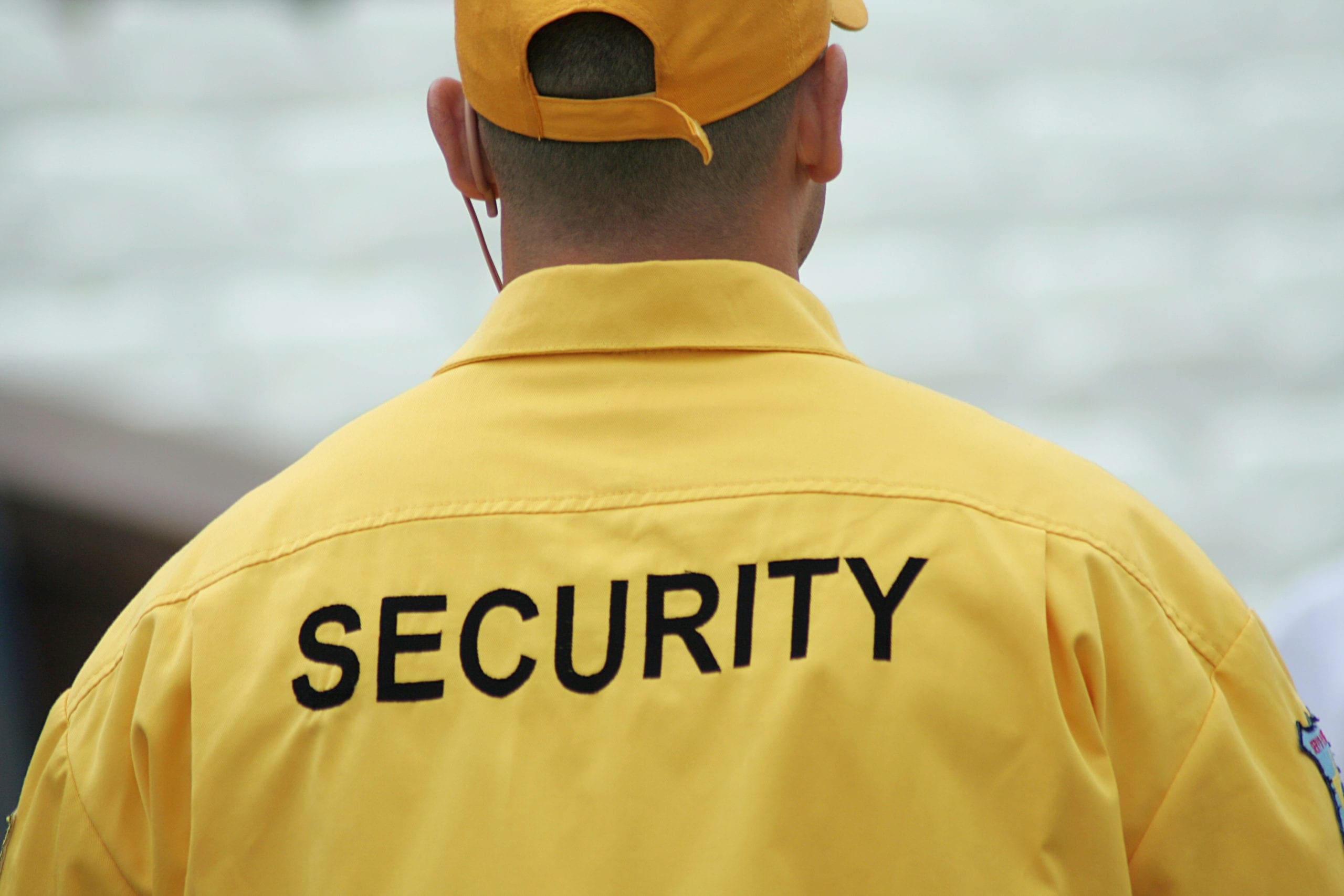 a man wearing a jacket with "security" on the back of it