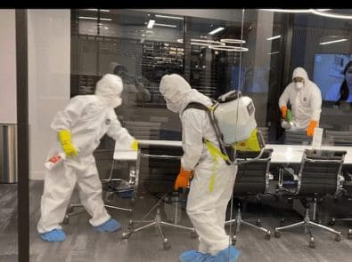 Planned employees in PPE disinfecting an office
