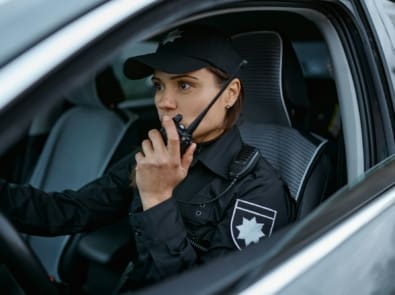 Policewoman using radio patrolling street in car