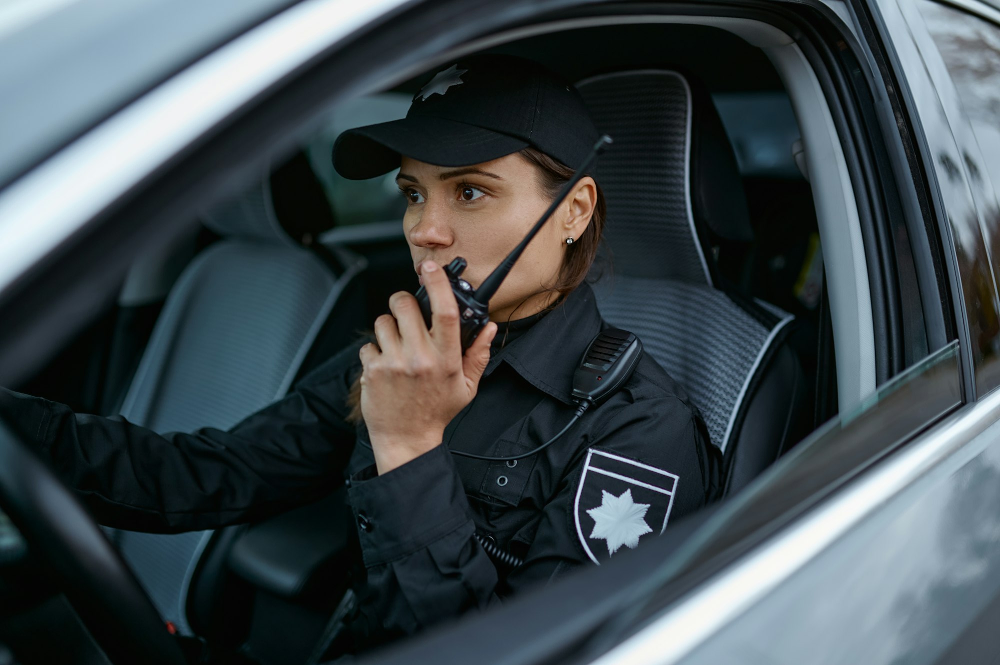 Policewoman using radio patrolling street in car